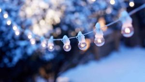 christmas festoon lights hanging outside in the white snow during winter time